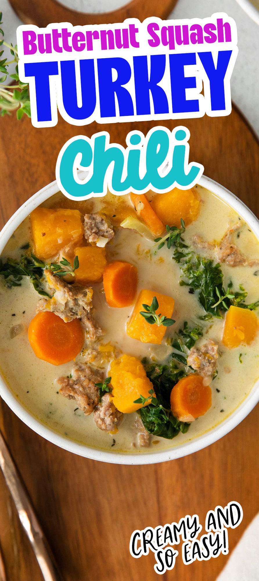  creamy turkey and butternut squash chili with carrots, thyme, kale, and peppers in a white bowl on a table