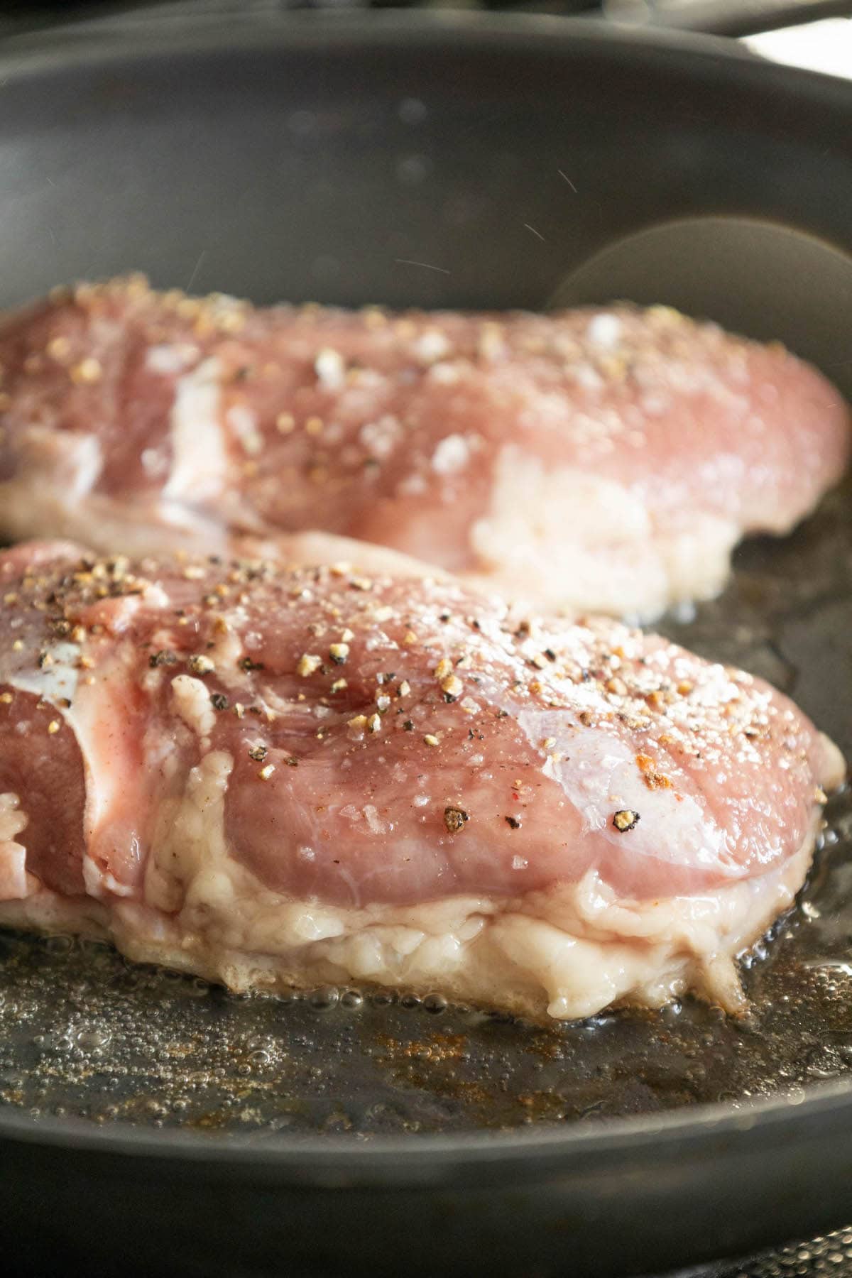raw duck breast searing in a pan