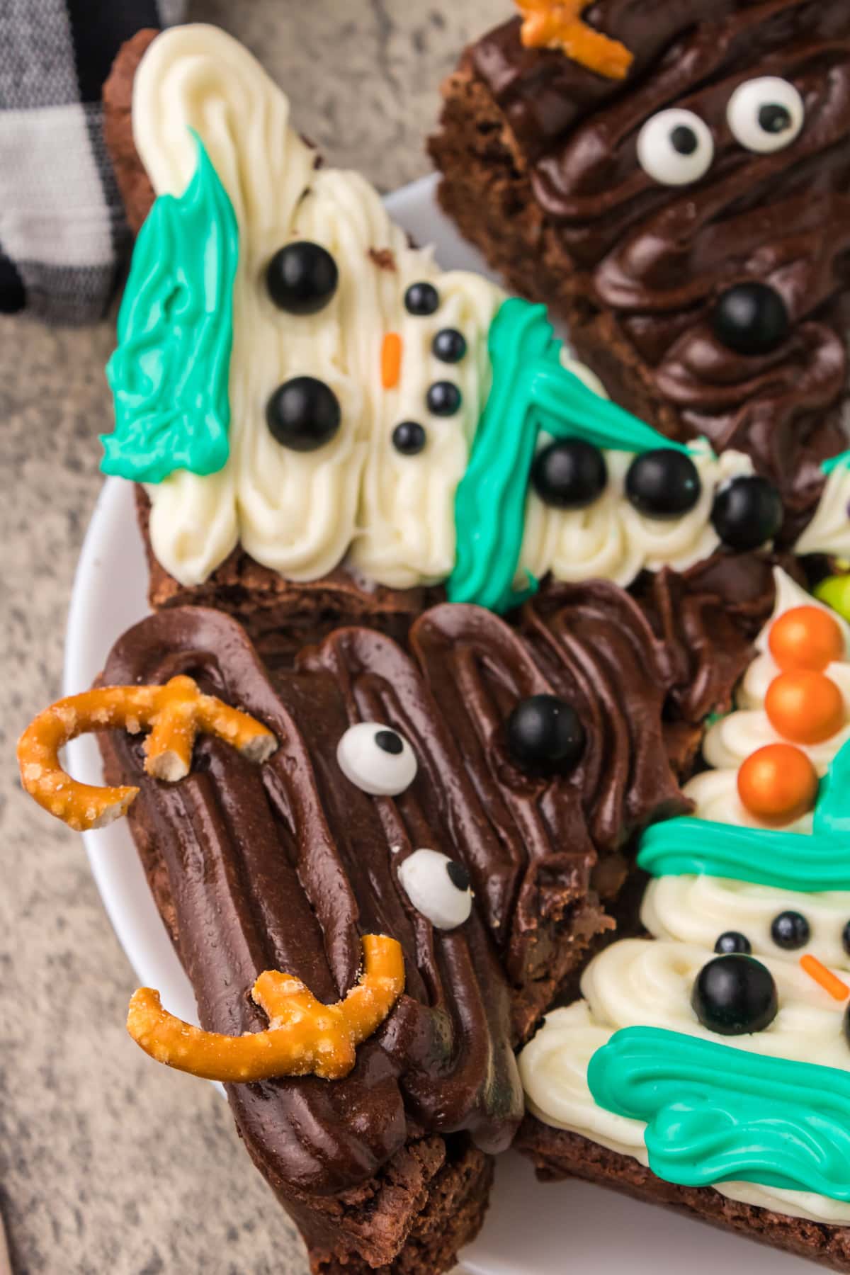 picture of brownies frosted to look like snowmen, christmas trees, and reindeer on a plate on a table