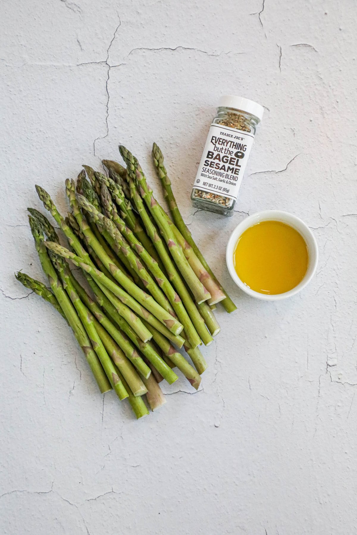 picture of asparagus, olive oil, and everything bagel seasoning on a table