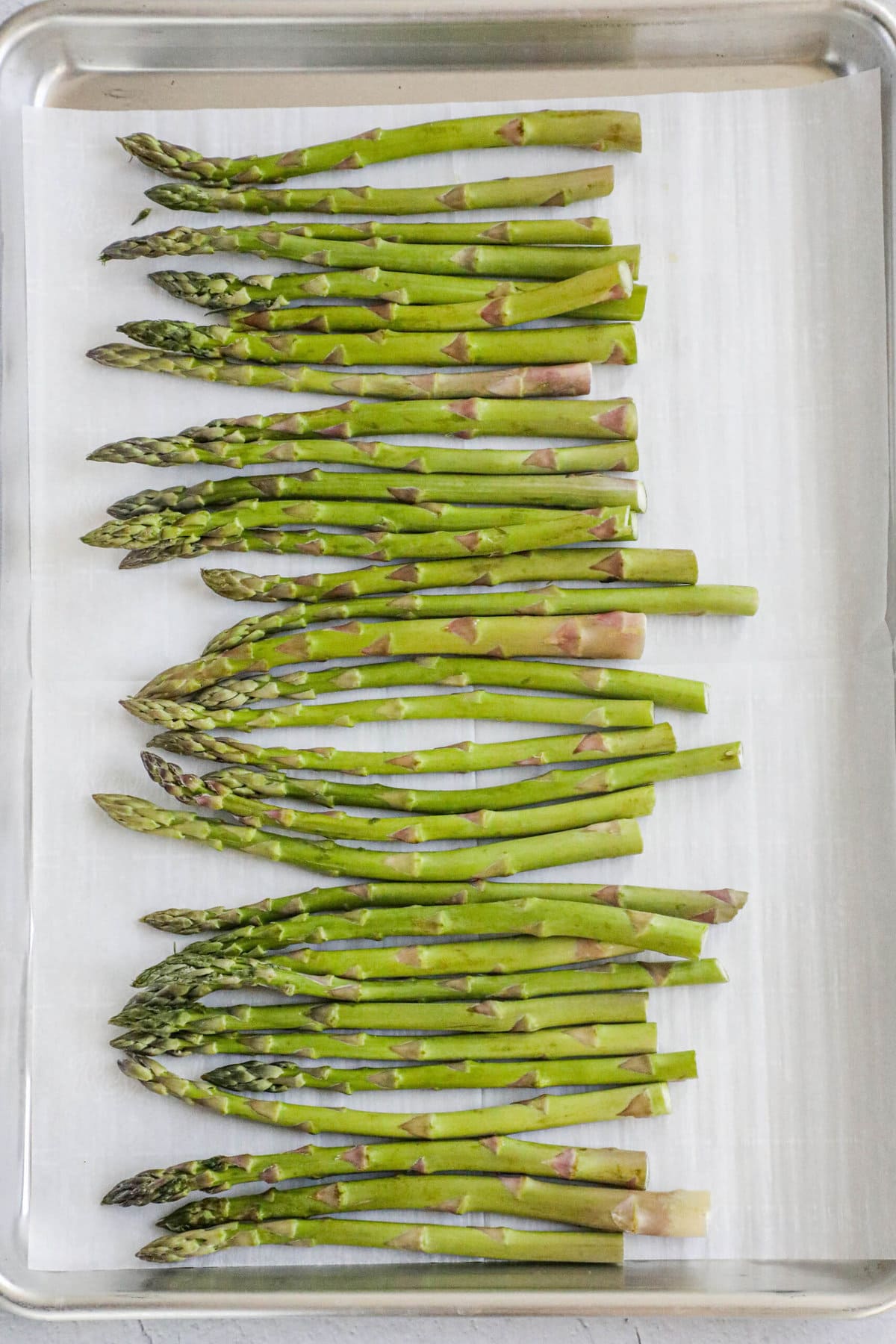 picture of asparagus spears on a baking sheet lined with parchment paper