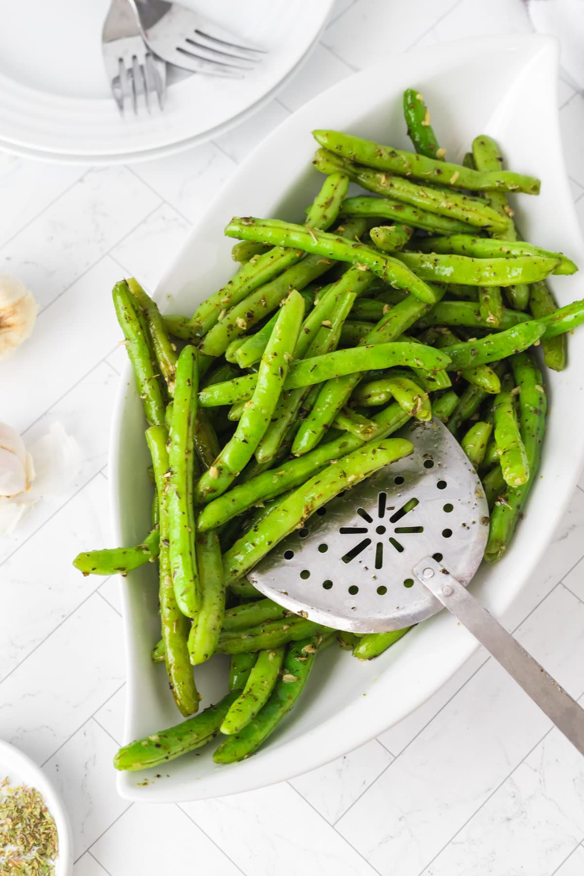 picture of green beans seasoned with garlic and herbs in a bowl with a spoon 