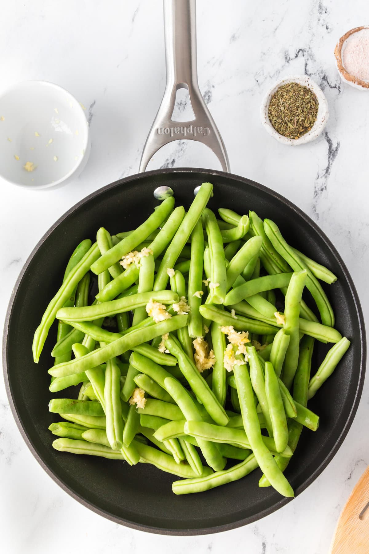 Thanksgiving keto garlic herb green beans sautéed in a frying pan with spices.