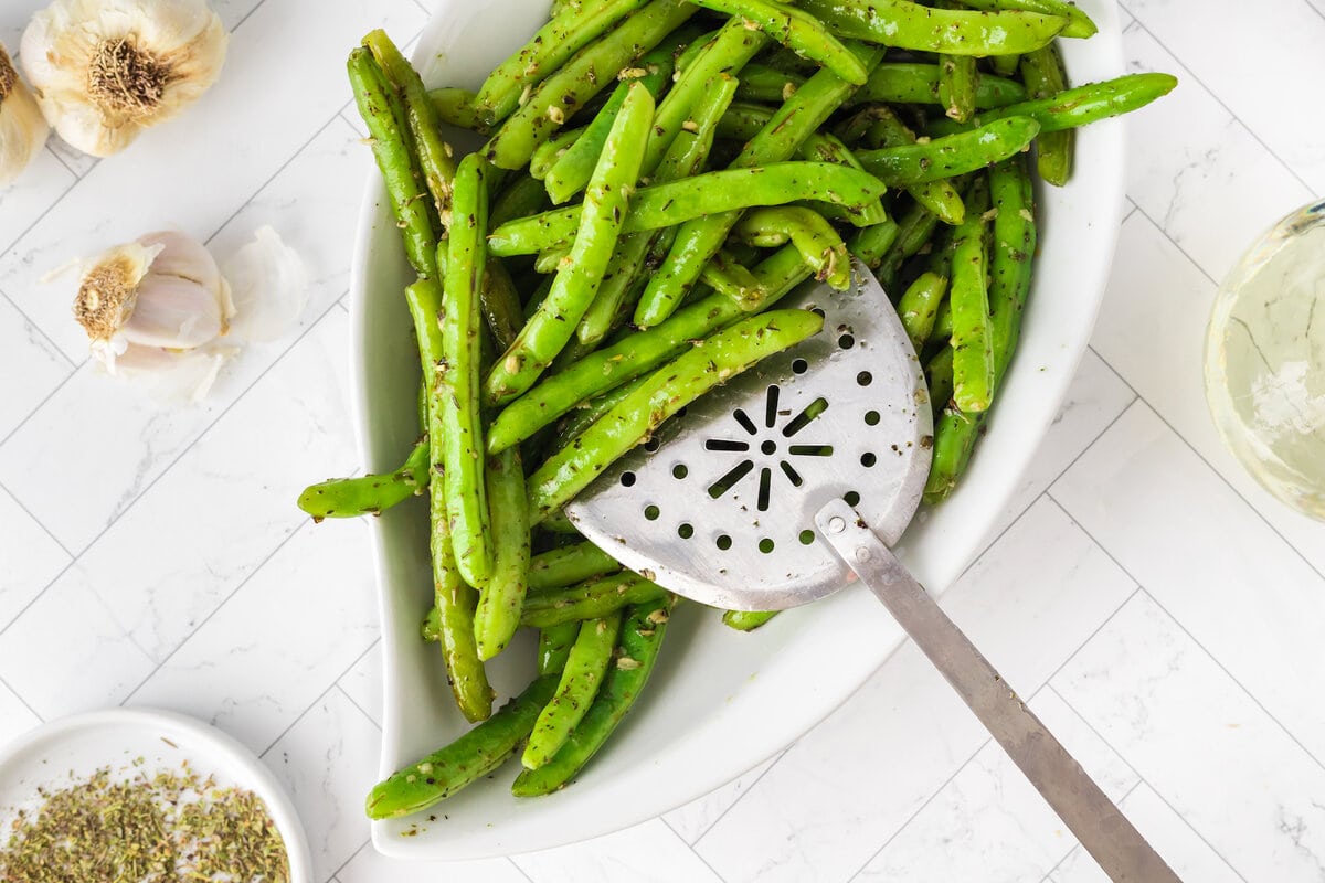 picture of green beans seasoned with garlic and herbs in a bowl with a spoon 