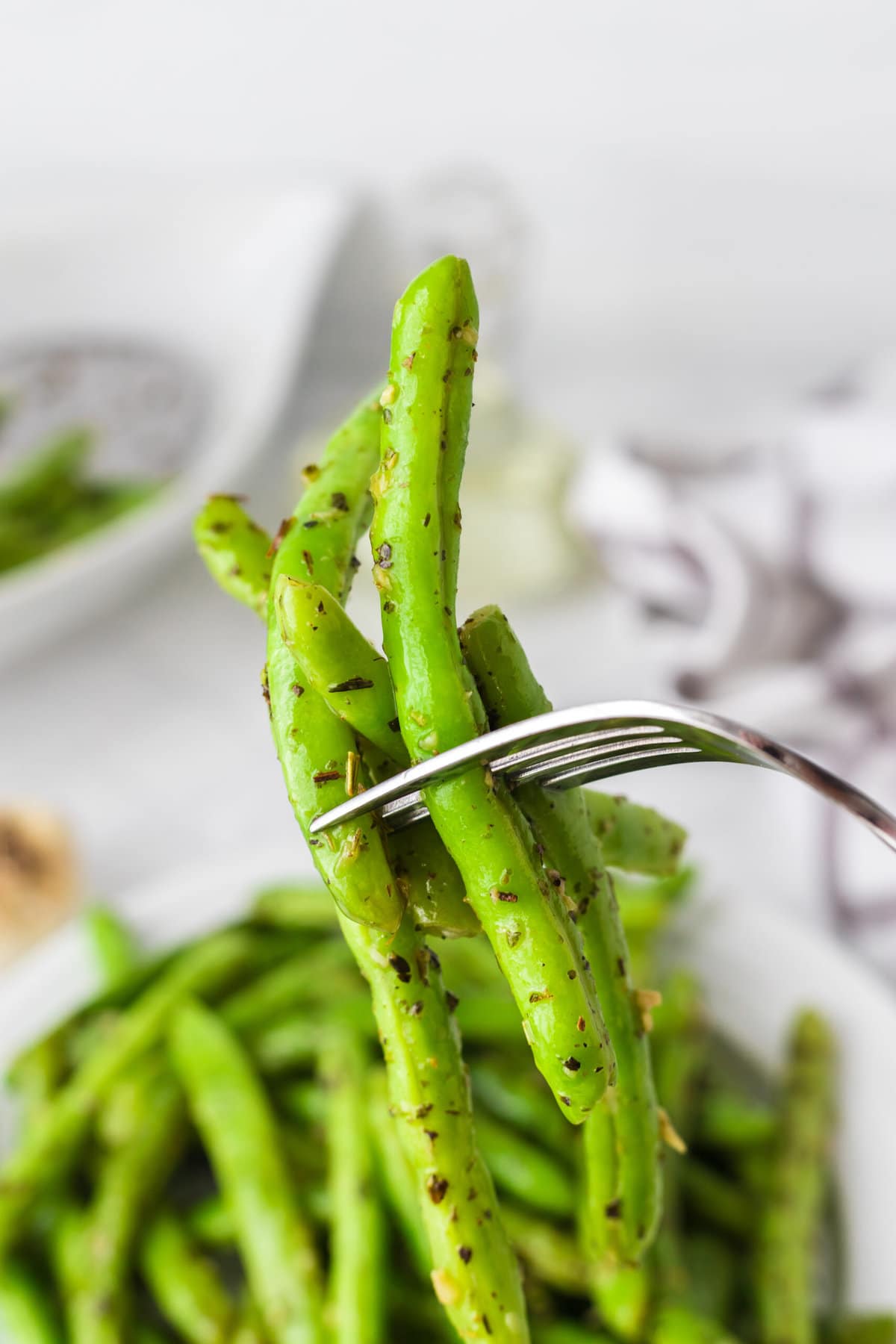 picture of green beans seasoned with garlic and herbs on a fork 