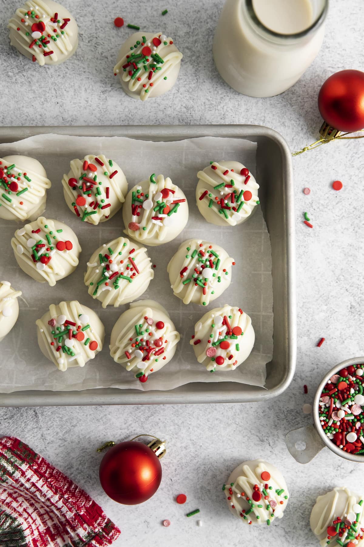 peanut butter truffles dipped in white chocolate and topped with christmas sprinkles on a baking sheet lined with parchment paper