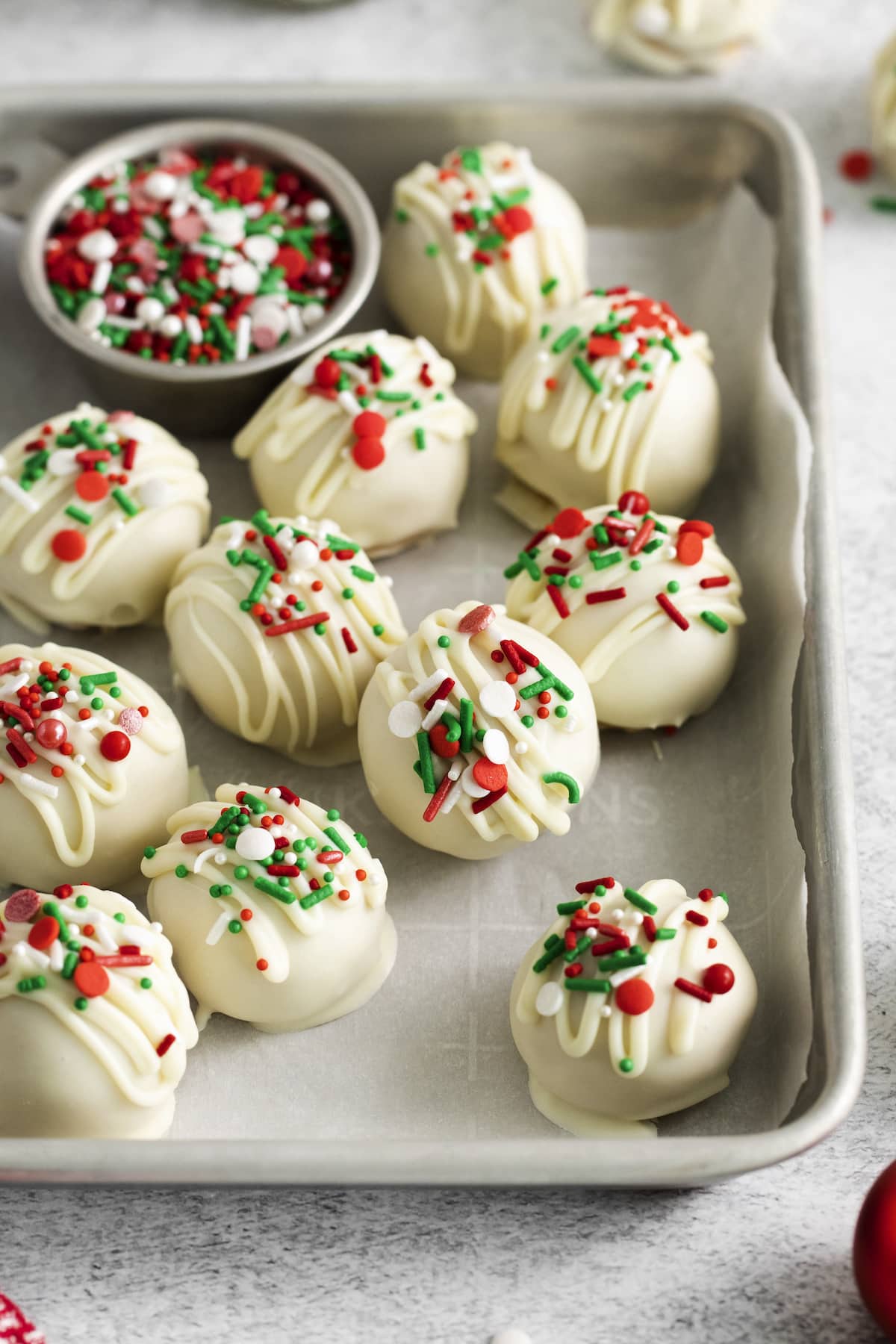 peanut butter truffles dipped in white chocolate and topped with christmas sprinkles on a baking sheet lined with parchment paper