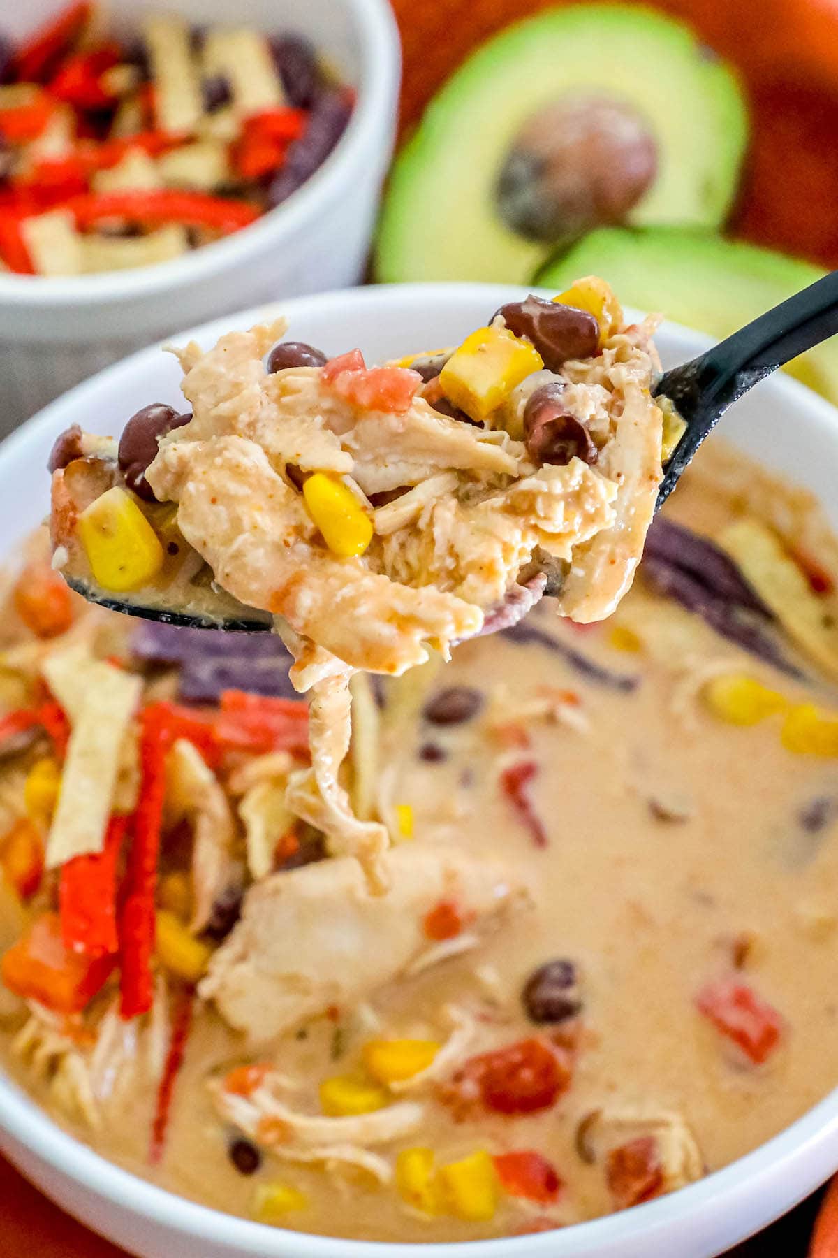 creamy chicken soup with beans, corn, rotel, and tortilla strips in a white bowl