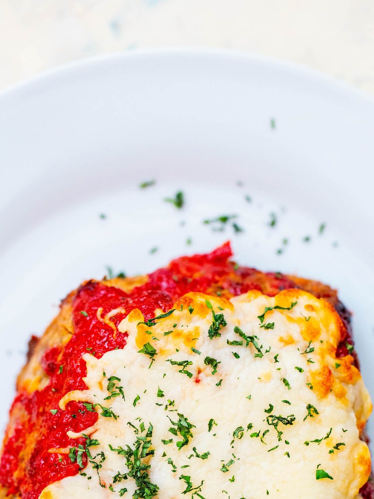 meatloaf covered in cheese on a white plate