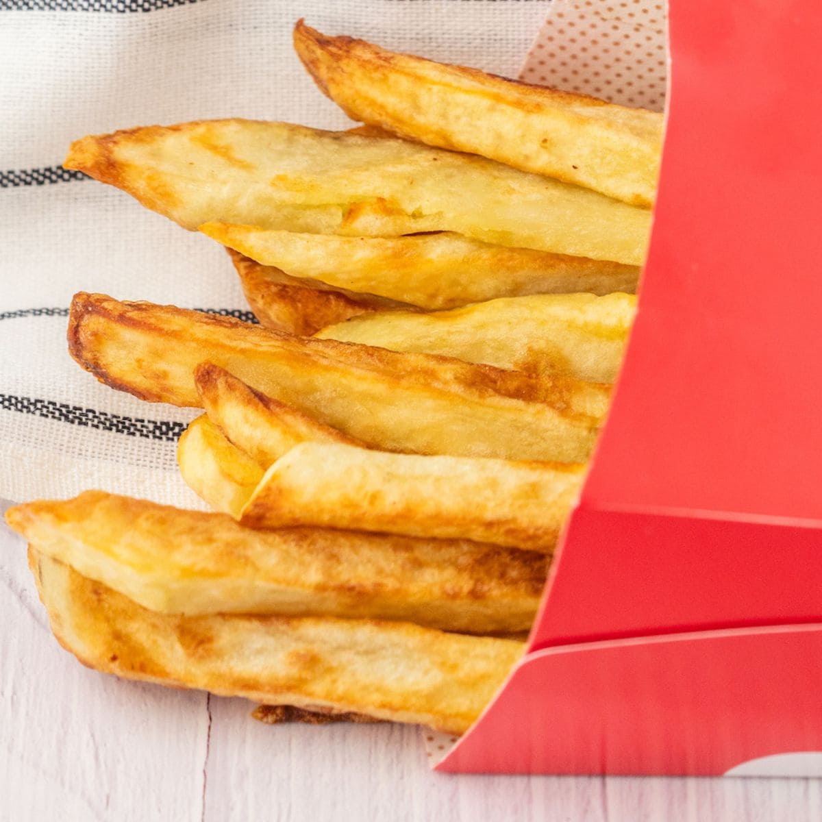 french fries in a red paper sleeve on a table
