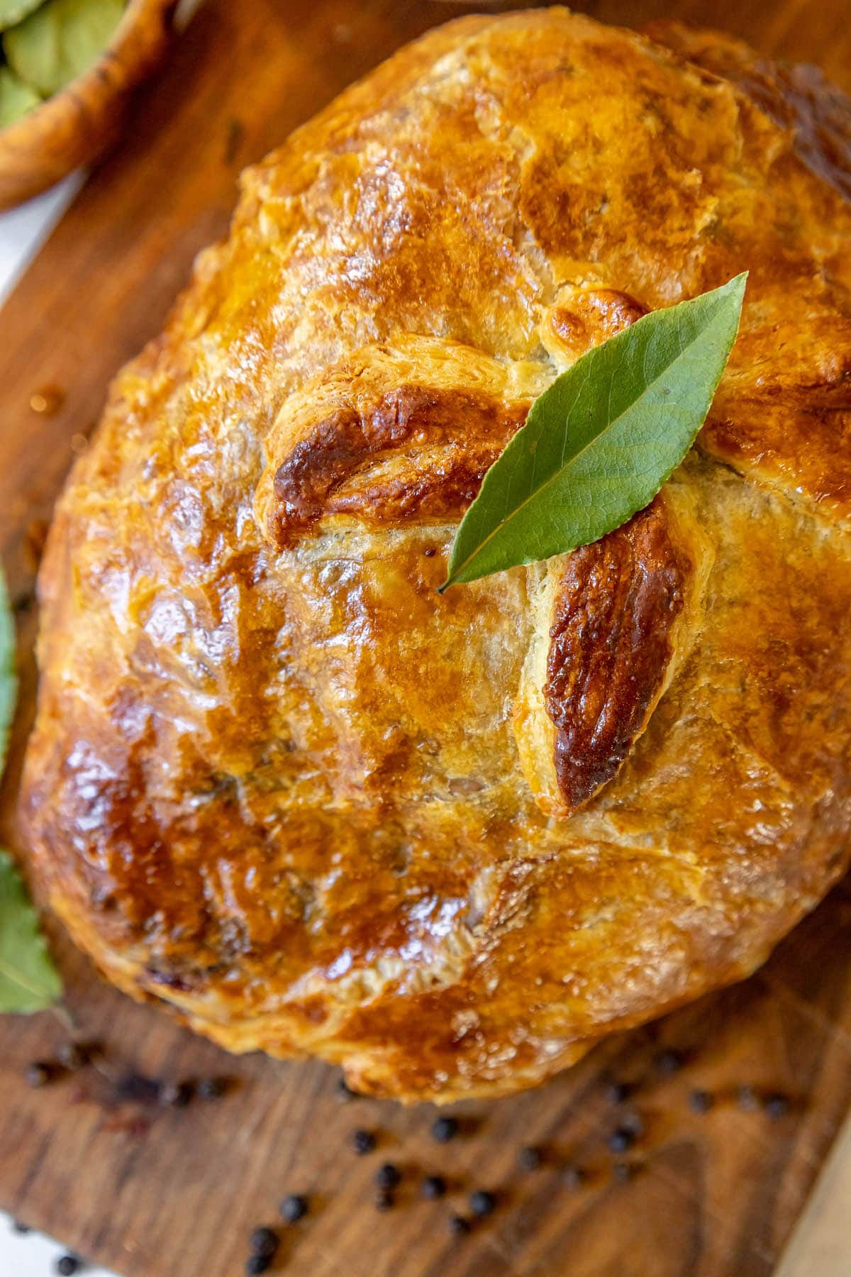 beef wellington wrapped in puff pastry with puff pastry leaf detail on top on a cutting board