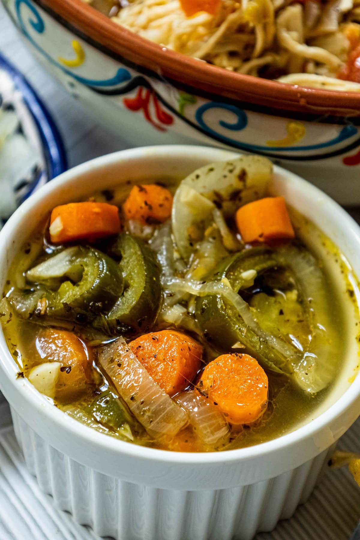 pickled jalapeños and carrots with onions, coriander, and pepper in a white dish