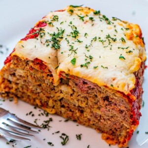 meatloaf loaf covered in cheese and basil with a fork