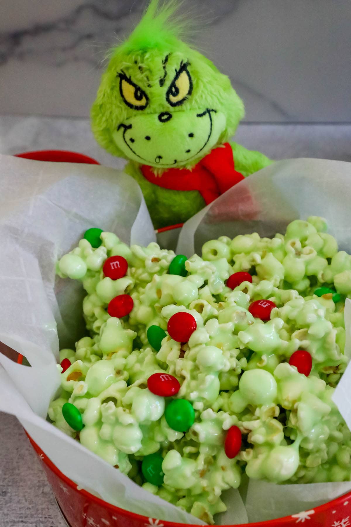 green candy popcorn with green and red m&ms in a bowl 