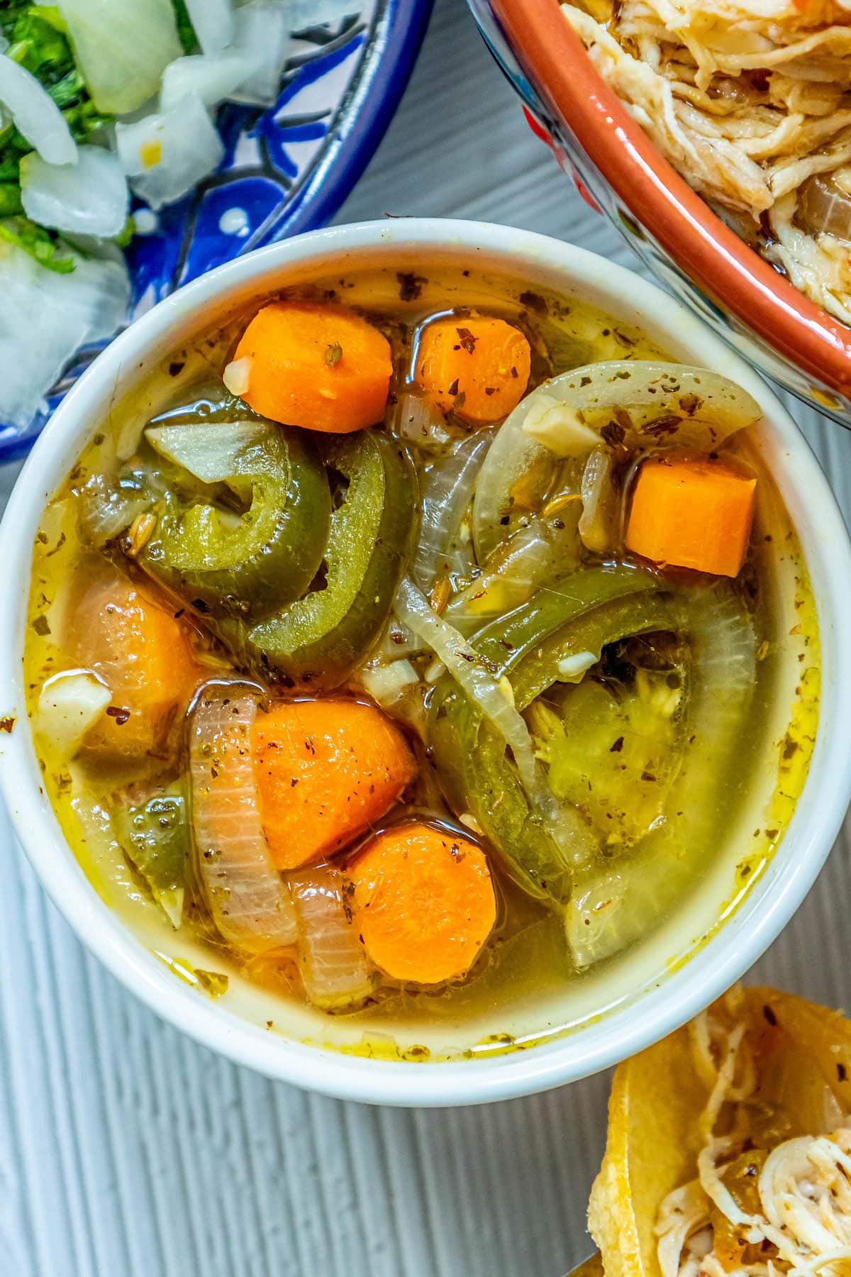 a white bowl with pickled carrots, jalapenos, and onions with spices in it 