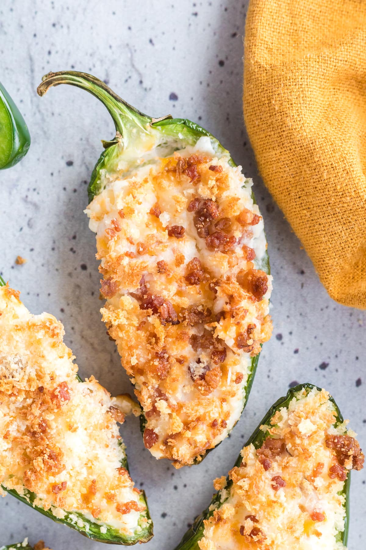 air fried jalapeño peppers sliced in half stuffed with cream cheese mixture and bread crumbs on a speckled plate