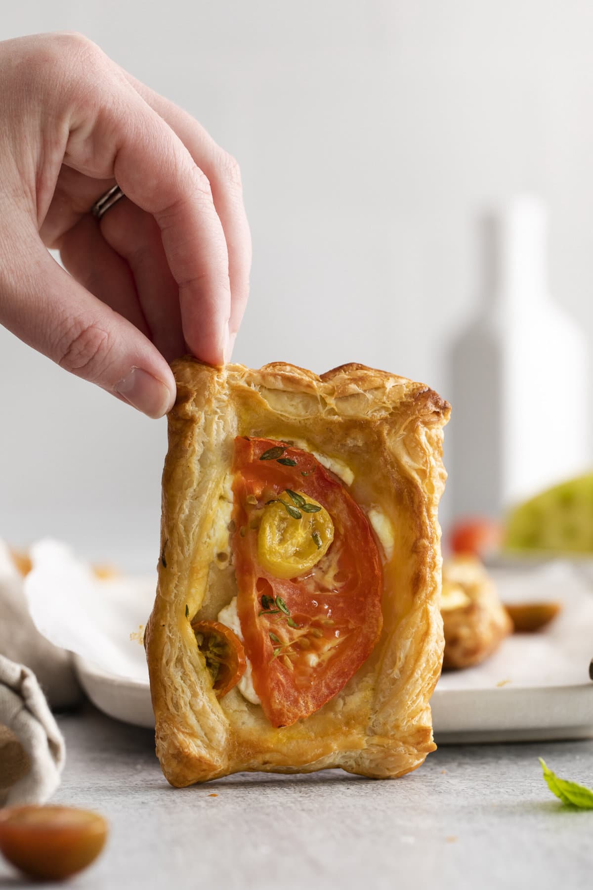 hand holding up a goat cheese and tomato tart