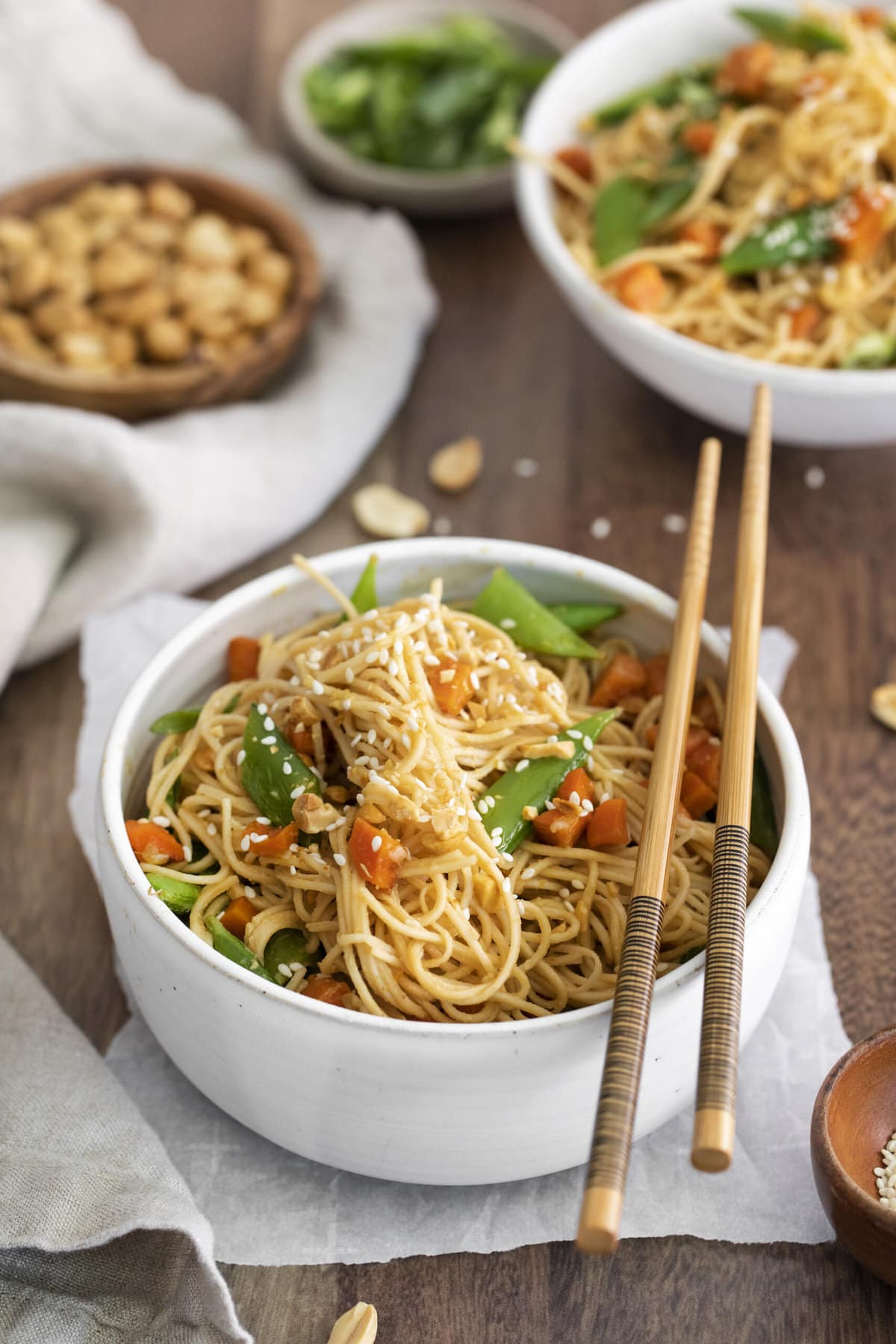 thai noodles with carrots, peas, and chop sticks on the bowl.