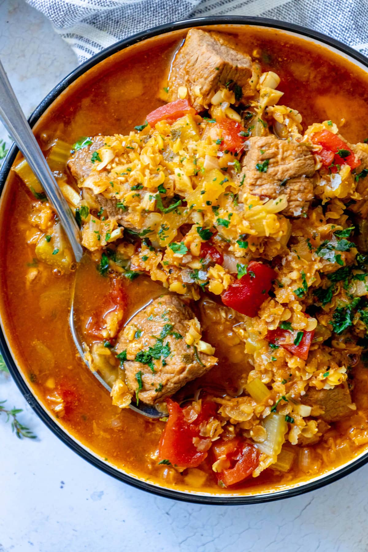 beef and lentil stew in a bowl with a spoon in it. 