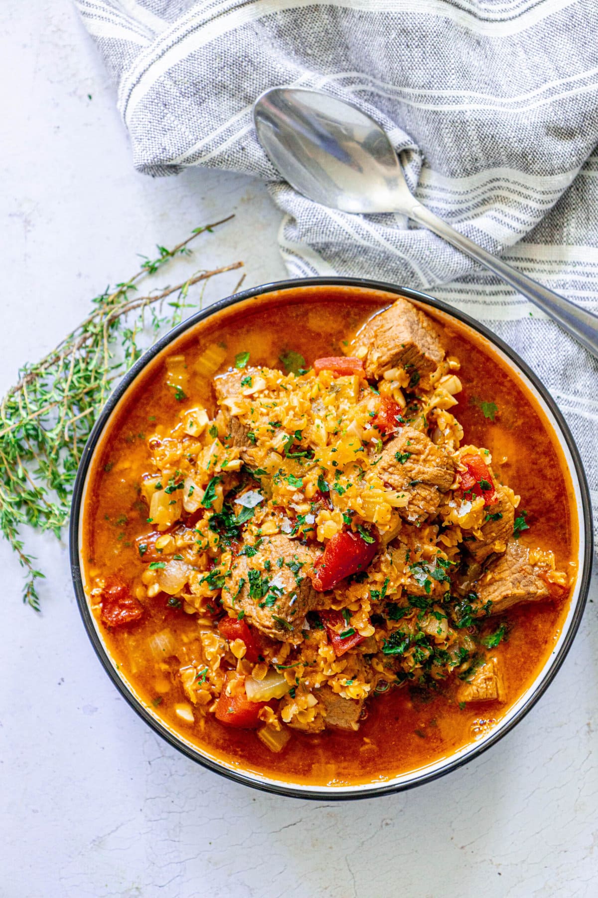 a whole bowl of lentil and beef stew with a white background. 