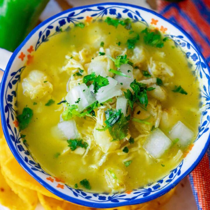posole verde with chopped onion, cilantro, shredded chicken and hominy in a bowl