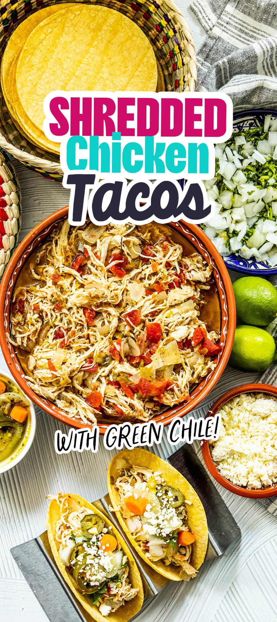 shredded chicken with tomatoes and green chile in a telavera bowl next to chicken tacos in a taco stand and a bowl of jalapeno and carrot salsa, a bowl of crumbled white cheese, some limes, a bowl of diced onions, and a bowl of tortillas on a table