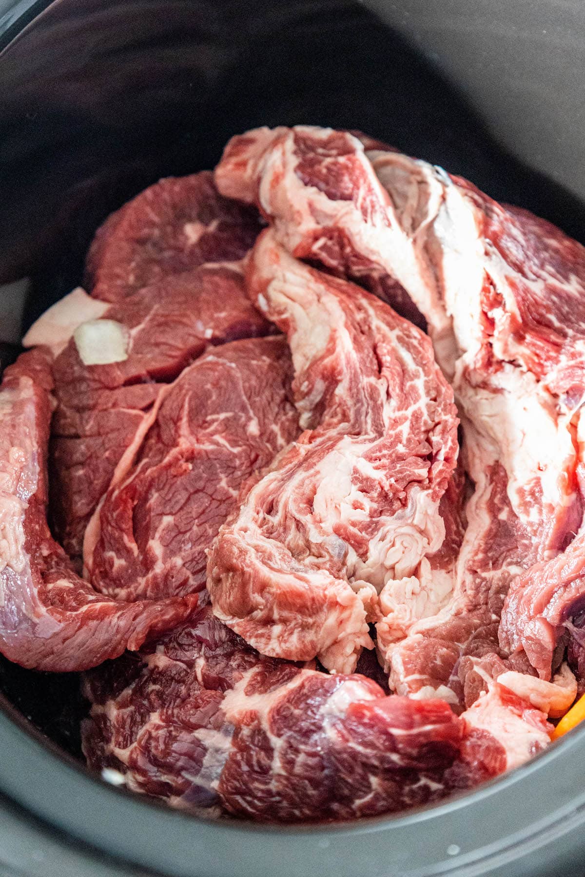 Slow cooker chuck roast steak in gravy served in a black bowl.