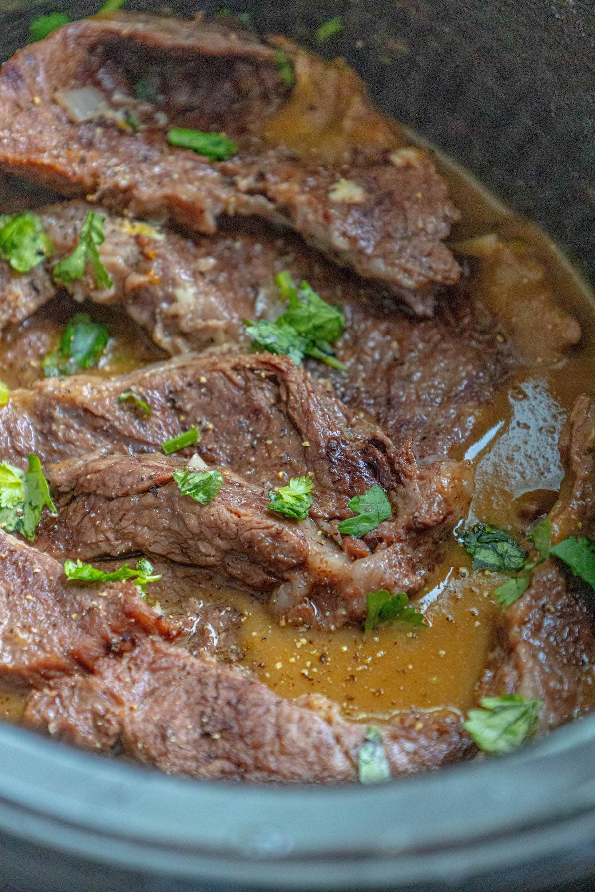 chuck roast steaks with gravy and parsley in a slow cooker