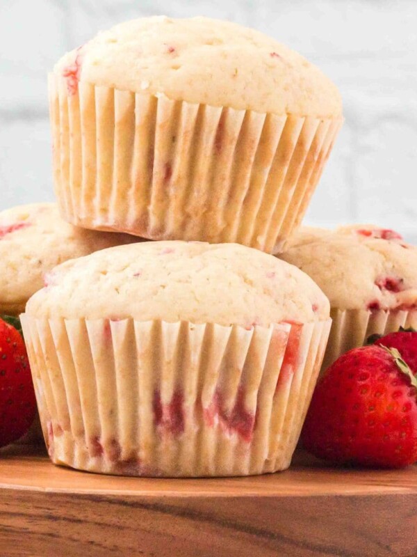 strawberry muffins stacked on top of each other with strawberries on a wood platter