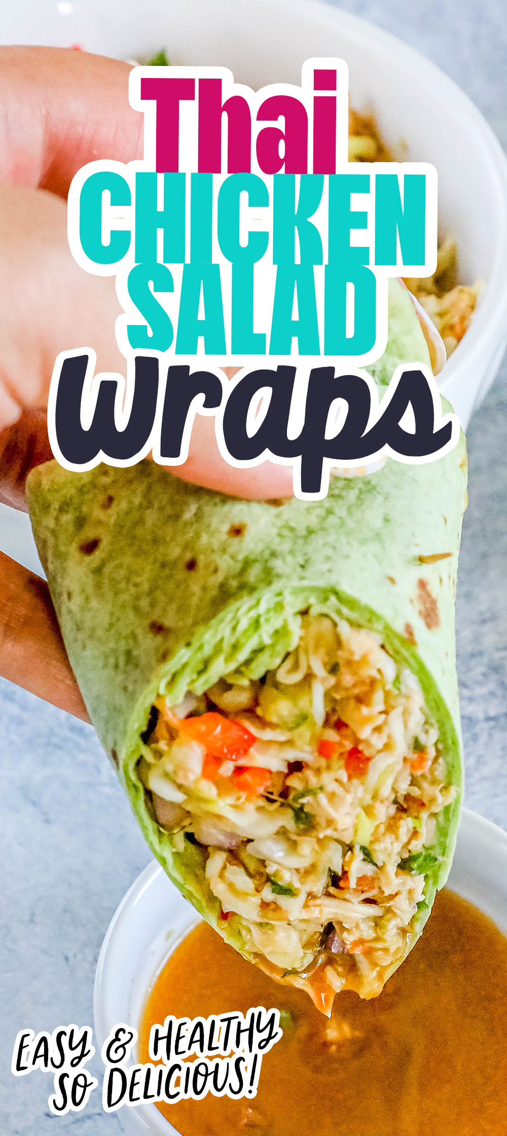 chicken salad with shredded chicken, cabbage, and diced vegetables wrapped in a green tortilla sliced in half being dipped into a bowl of peanut sauce