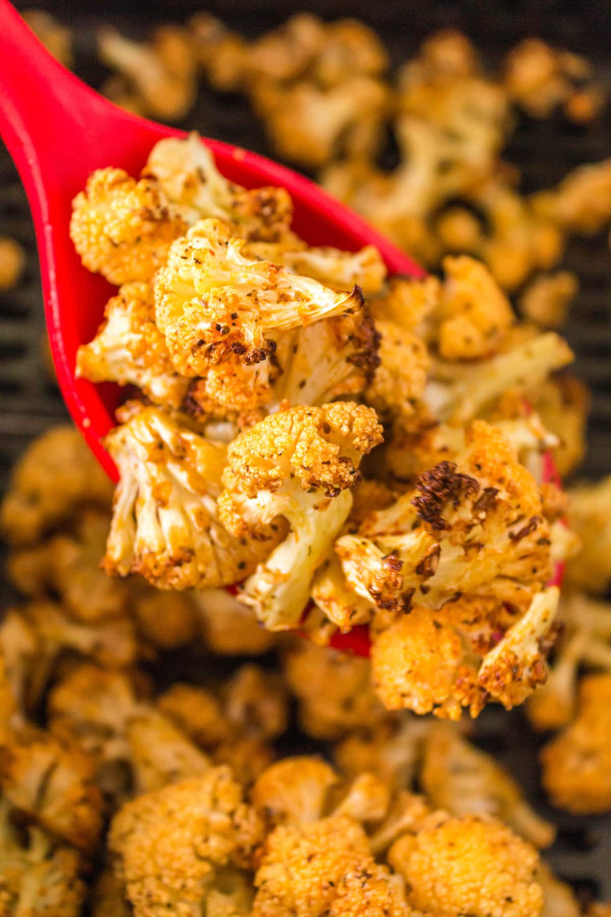 browned air fried cauliflower on a red spoon