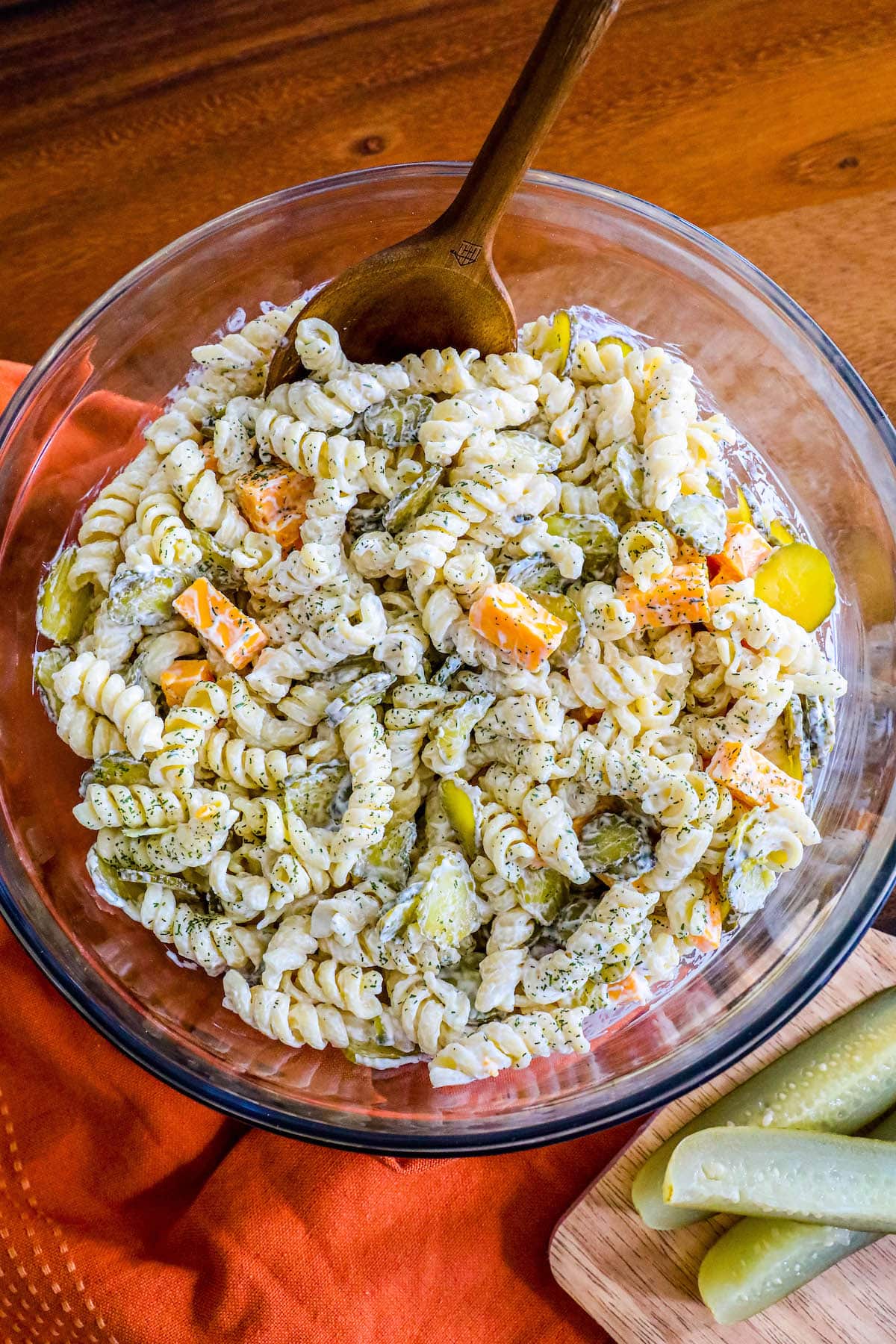 pasta salad mixed with chopped pickles and cheese tossed in dill mayonnaise sour cream dressing in a glass bowl 