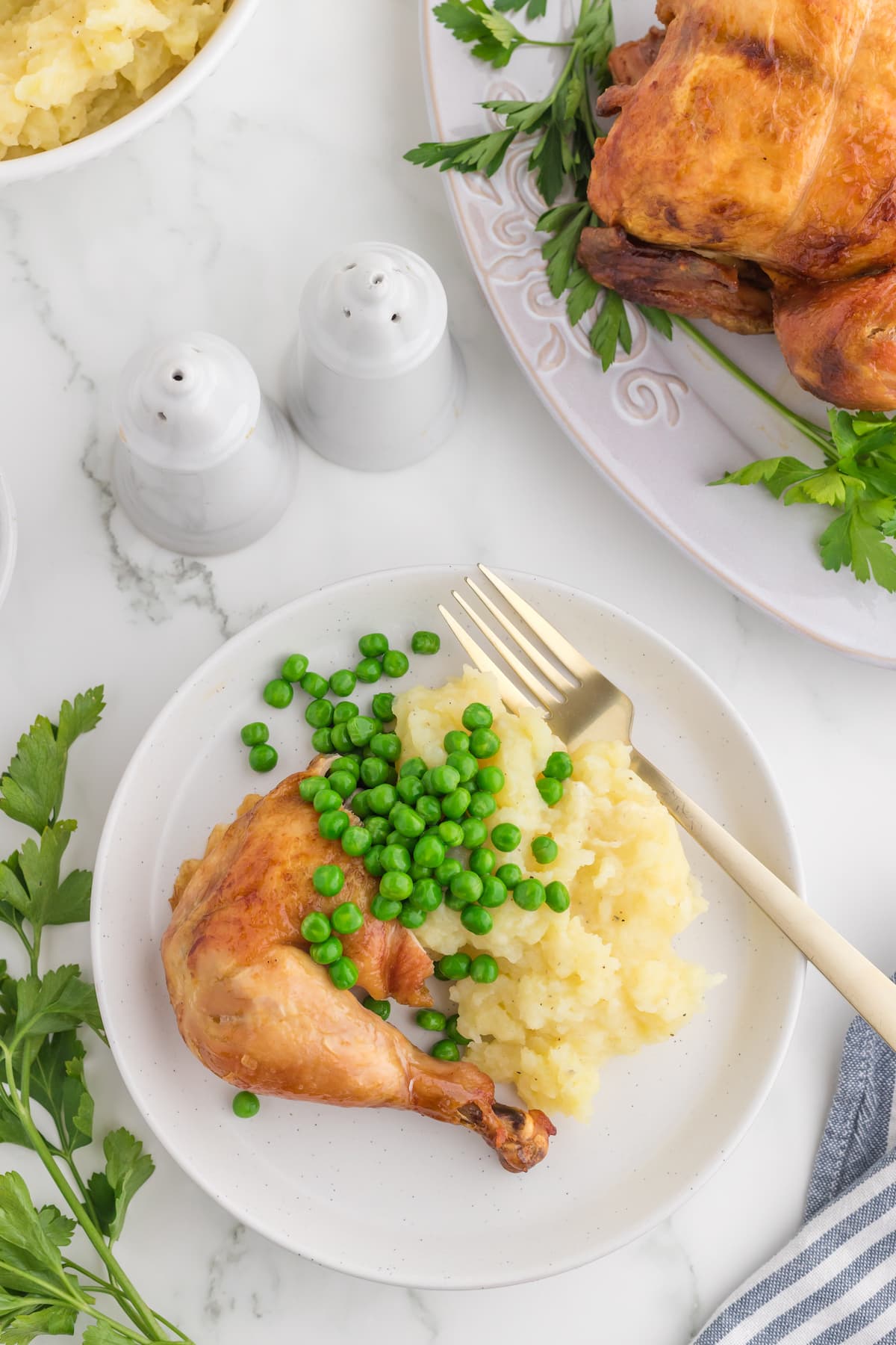 roasted chicken leg on a white plate with peas and mashed potatoes in front of an instant pot