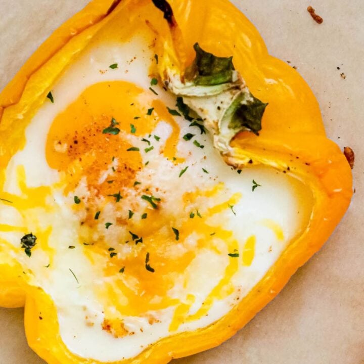 baked eggs inside halves of bell peppers with melted cheese and herbs on top
