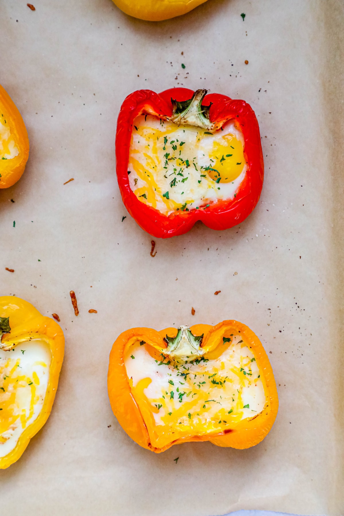 baked bell peppers with an egg in them and parsley on them