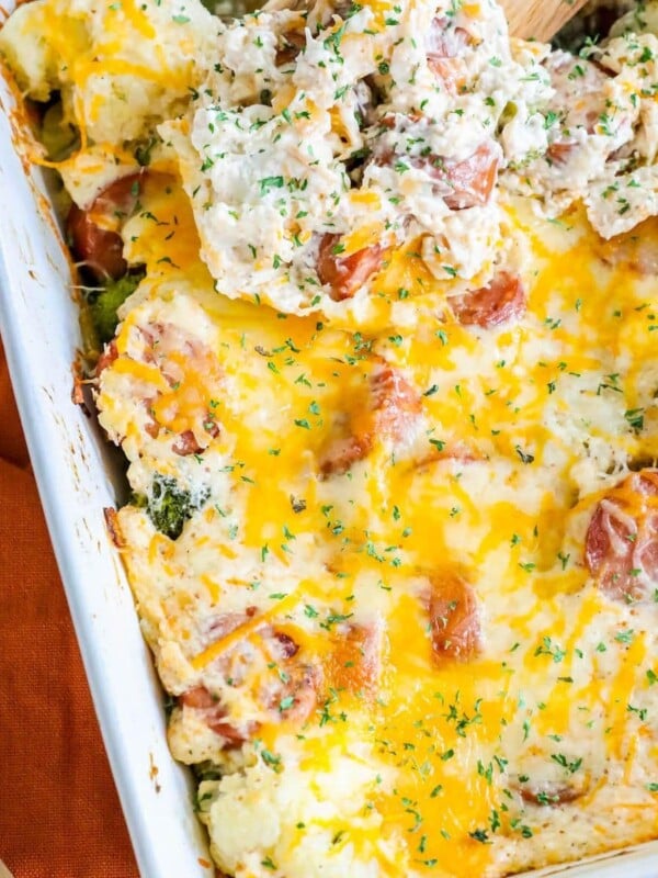 cheesy casserole with sliced sausage, broccoli, cauliflower, and herb seasonings in a white casserole dish on a table