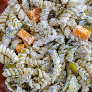 creamy rotini pasta salad with chunks of cheese and dill pickles in a bowl