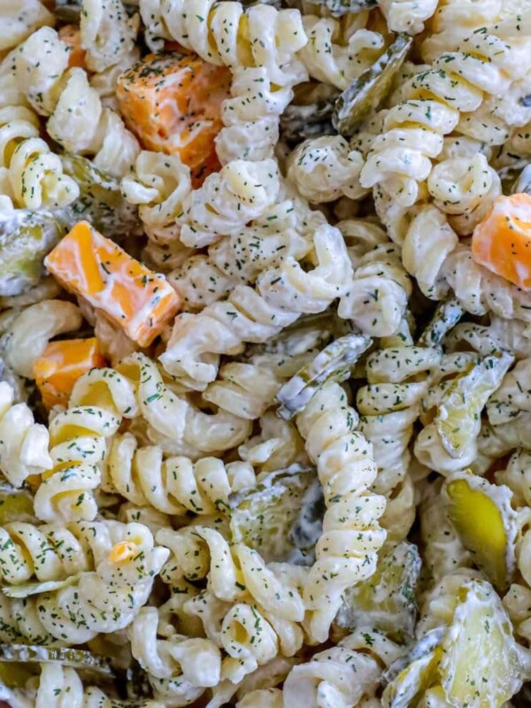 creamy rotini pasta salad with chunks of cheese and dill pickles in a bowl