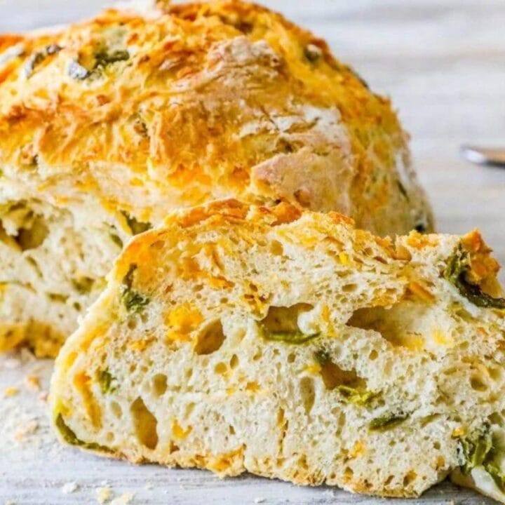 baked bread round with peppers and cheese cut in half on a table