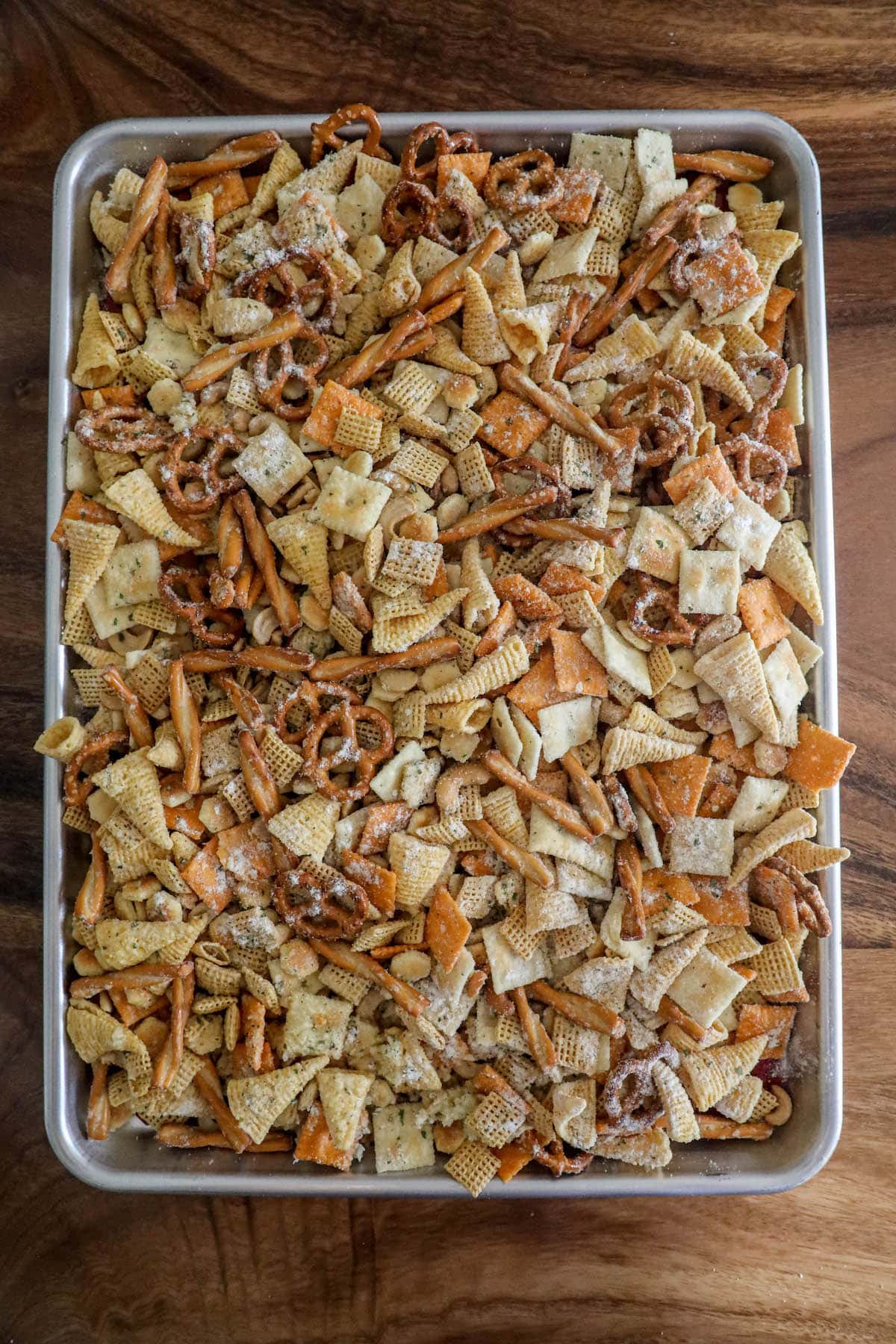 chex mix with ranch seasoning spread out on a baking sheet