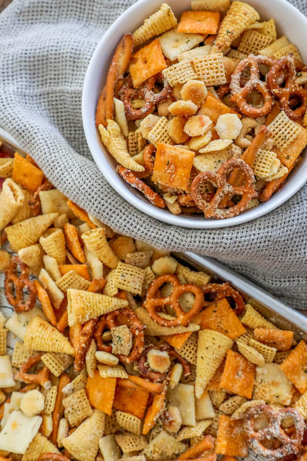 ranch seasoned chex mix in a bowl next to chex mix spread out on a baking sheet