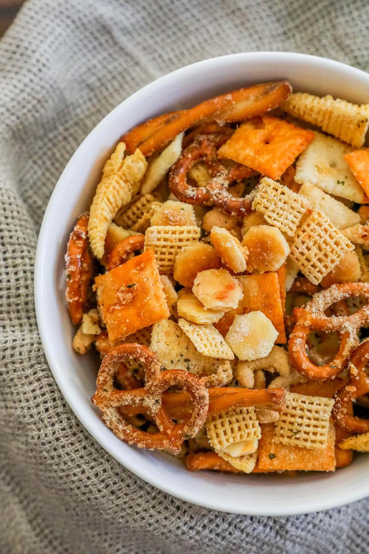 ranch seasoned chex mix in a white bowl with crackers, pretzels, and corn cereal in a bowl 