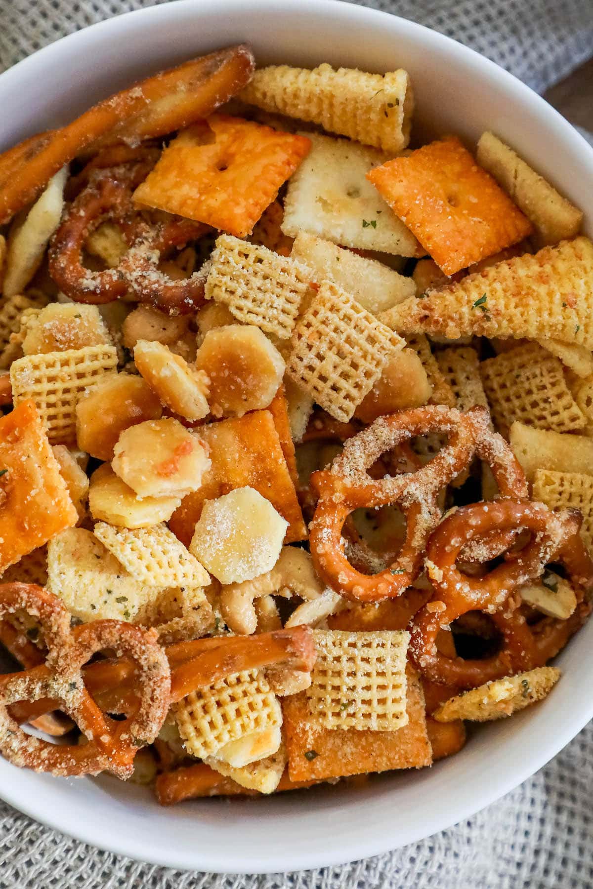 ranch dressing seasoned chex mix with cheese crackers and corn cereal in a white bowl 