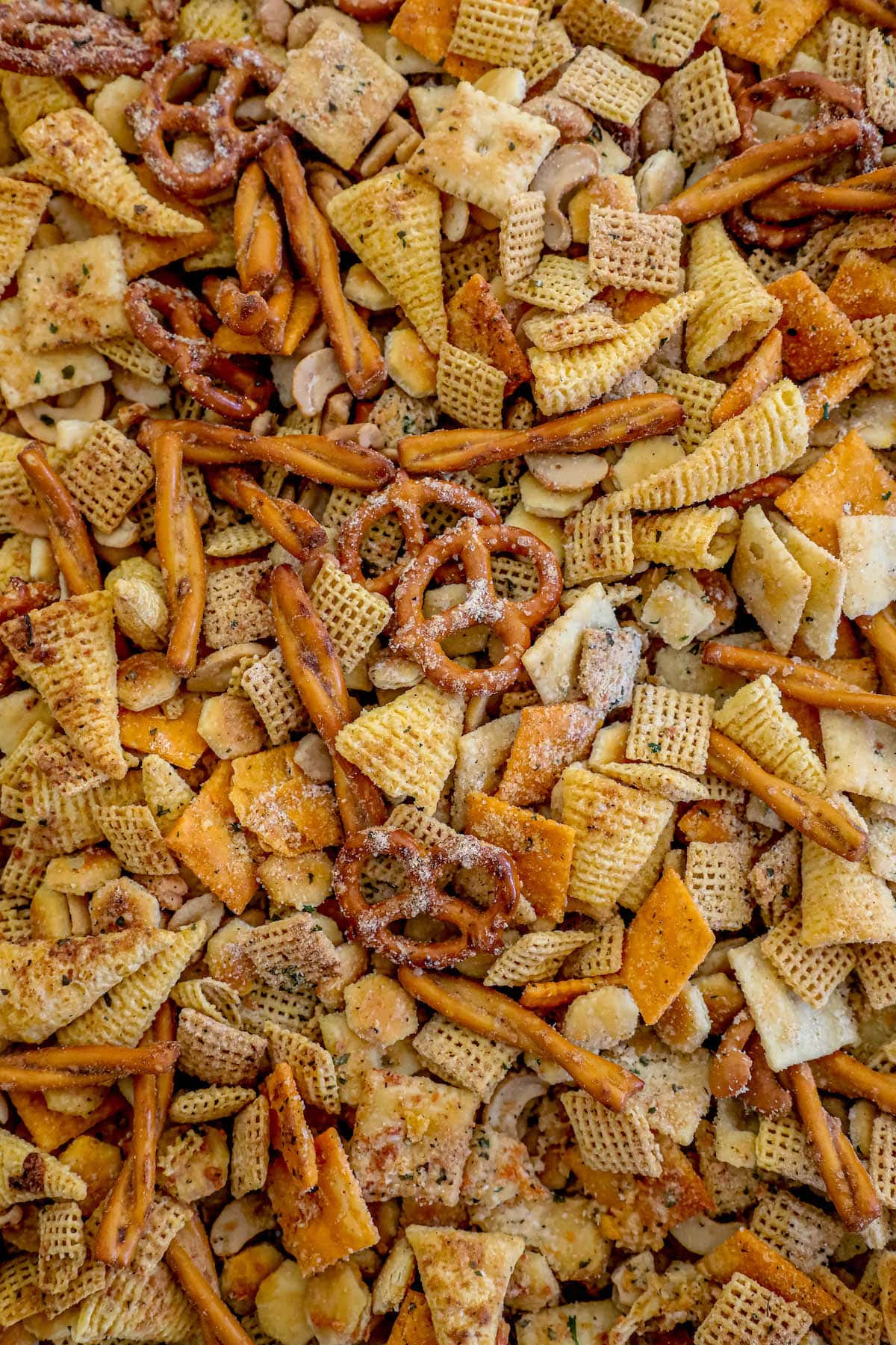 chex mix with pretzels, bugles, cheese crackers, and oyster crackers with ranch seasoning on a baking sheet