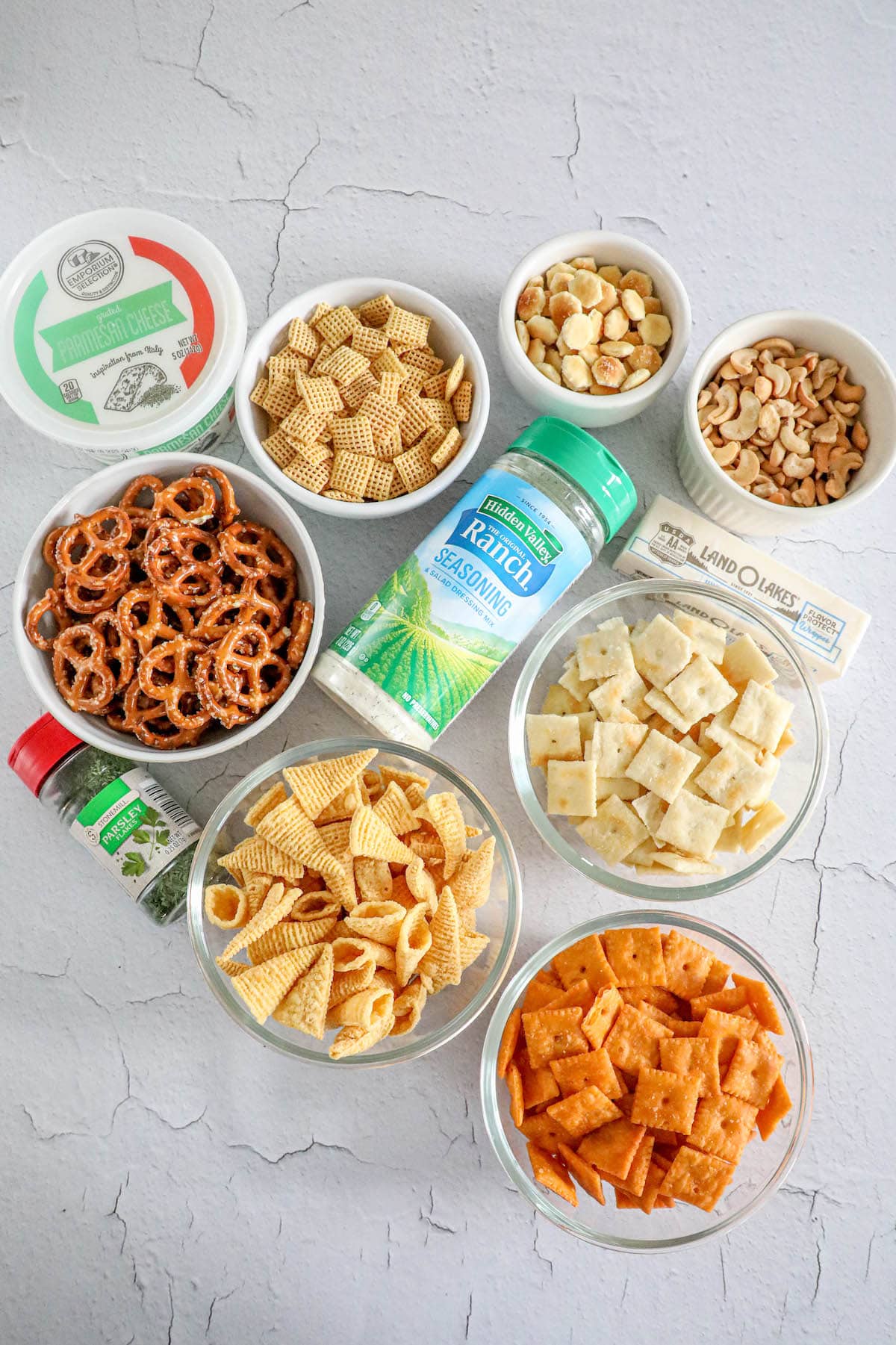 ranch seasoning, chex, pretzels, cheez its, nuts, and herbs on a table