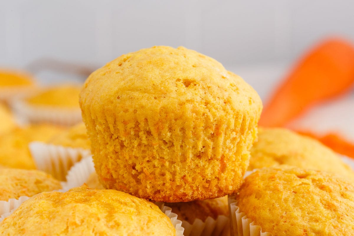 baked carrot muffins stacked on each other, one on top without a cupcake wrapper