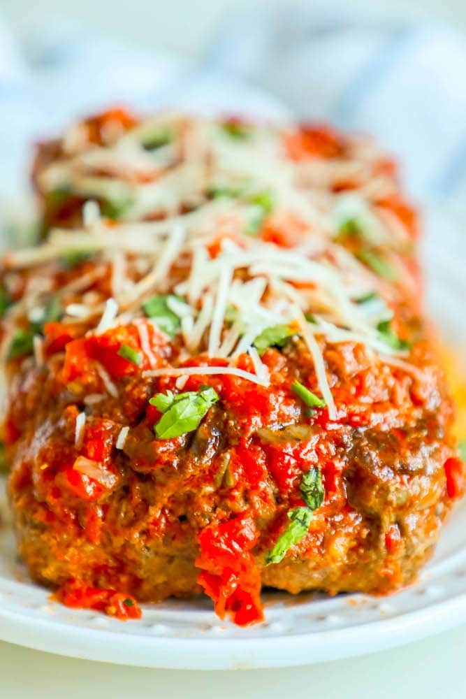 meatloaf baked in marinara and topped with cheese on a white plate