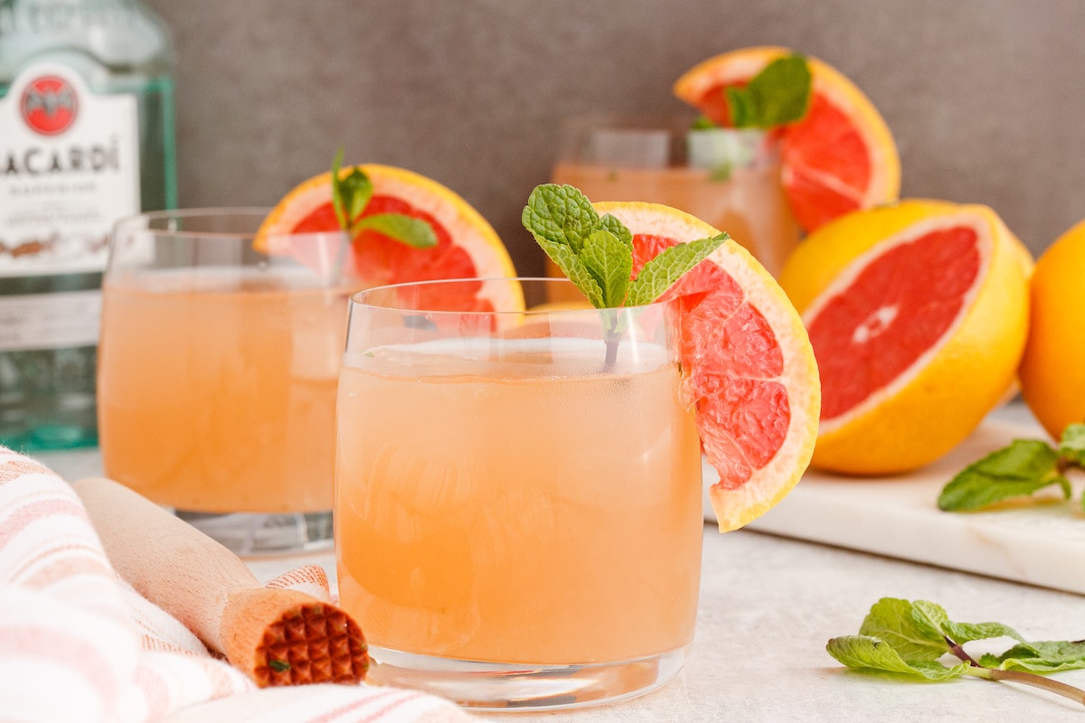 grapefruit mojito cocktail in a short glass with a sprig of mint and a slice of grapefruit on the side