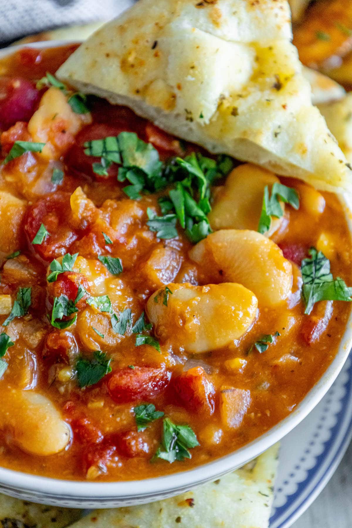 baked greek beans in a tomato sauce with chopped herbs and giant white beans