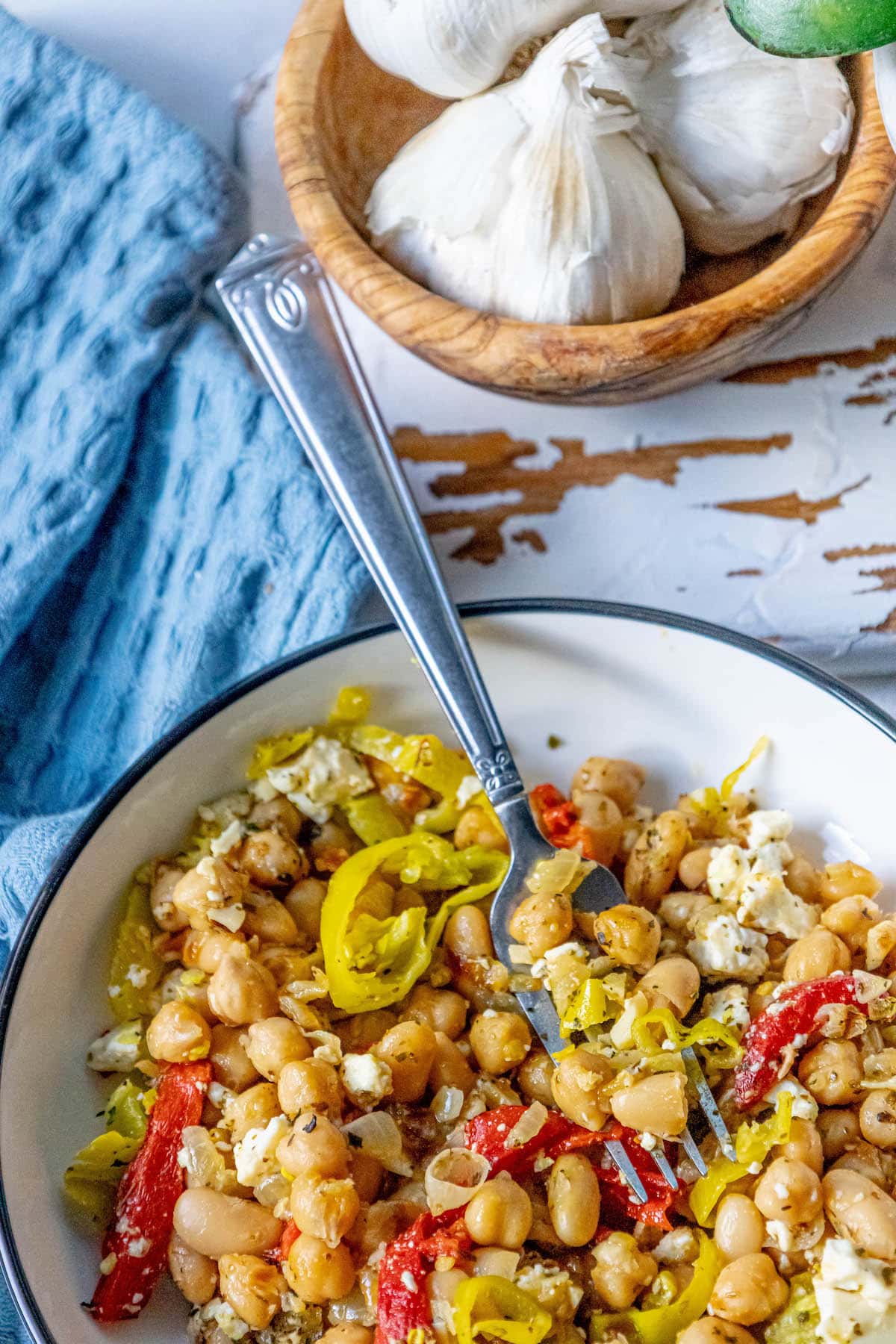 a bowl with chickpeas, feta, herbs, red pepper strips, and onion